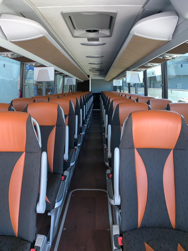 Coach interior with orange and grey reclining seats, USB power outlets and overhead air conditioning vents