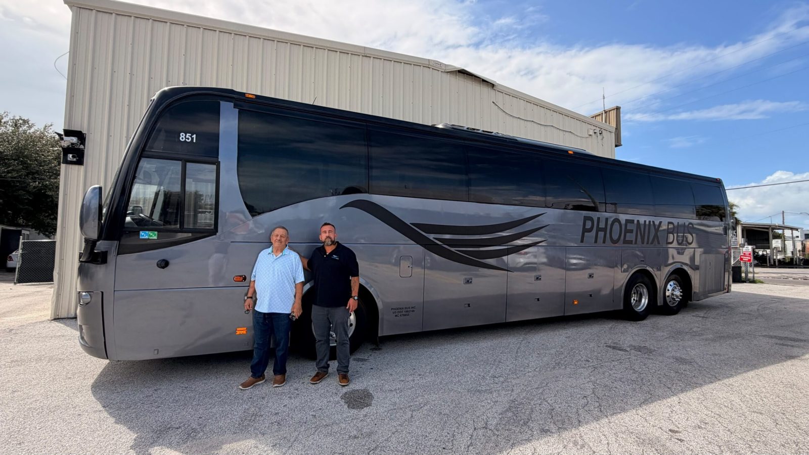 Phoenix Bus Orlando founder Wagner Triska Sr. and CEO Wagner Triska Jr. standing beside a Phoenix Bus motorcoach.